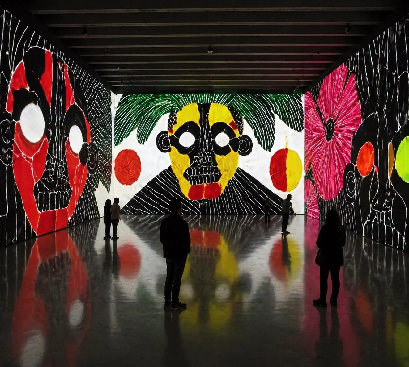 Simulation: a gallery hall where a yellow and black skull with green fronds fills the end wall, reflected in a polished concrete floor.