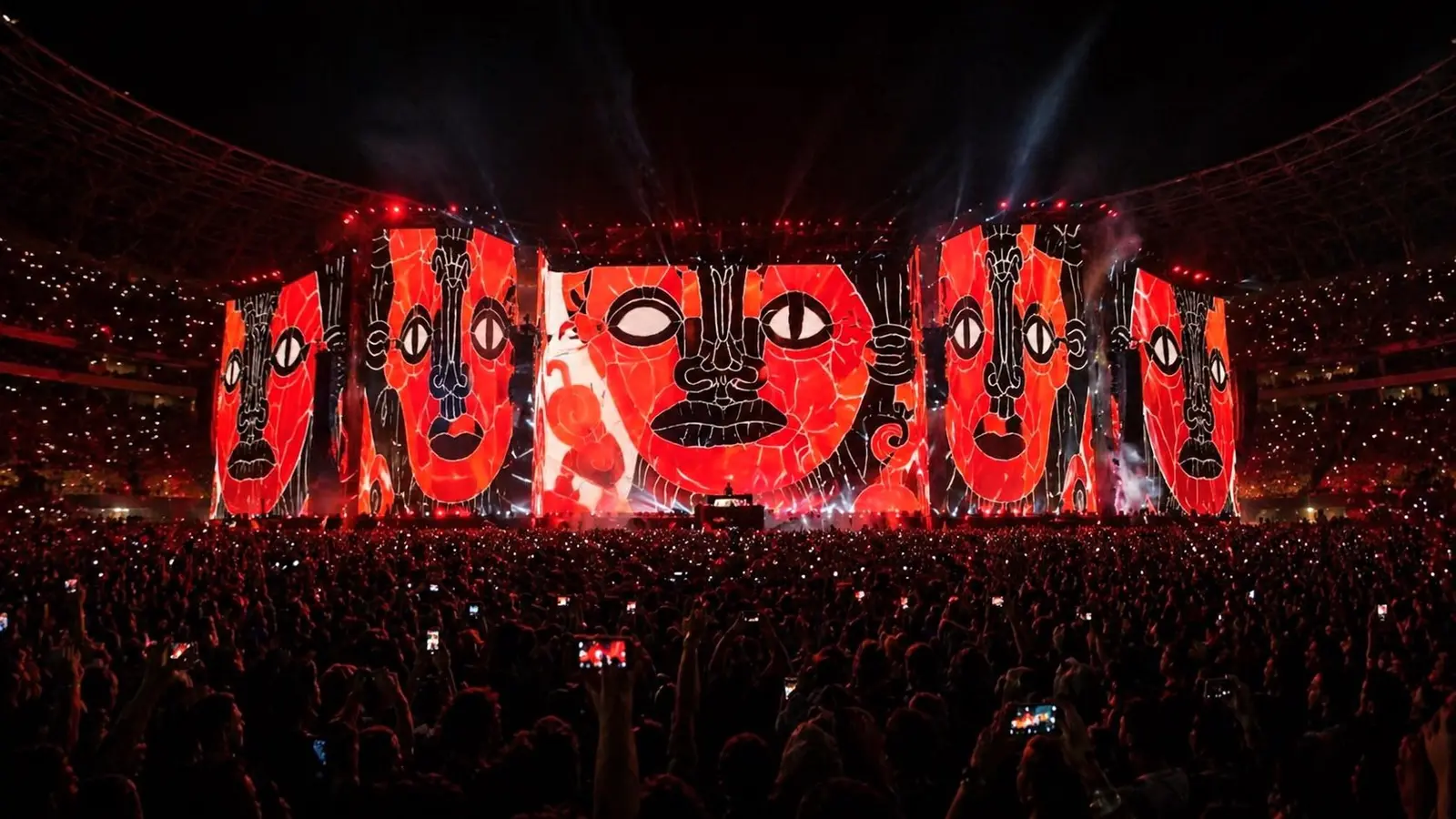 Simulation: a stadium stage filled with large red faces outlined in black line above a crowd.